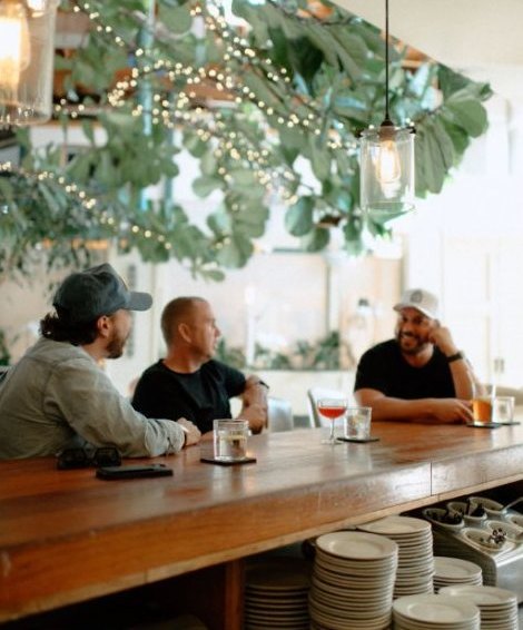 Guests at the bar under string lights and greenery